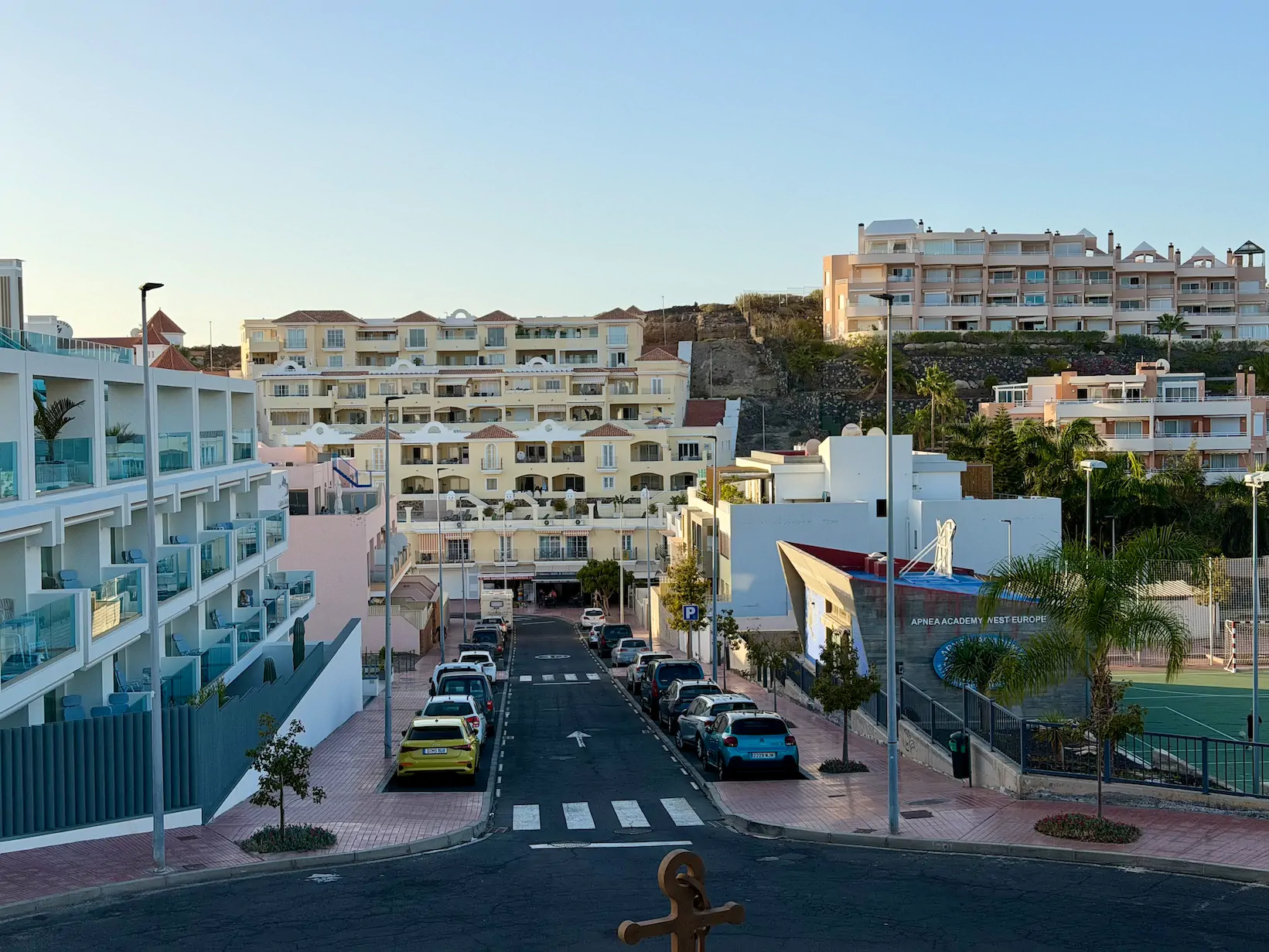 Ulica na Teneryfie z nowoczesnymi apartamentami po lewej stronie i budynkiem Apnea Academy po prawej
