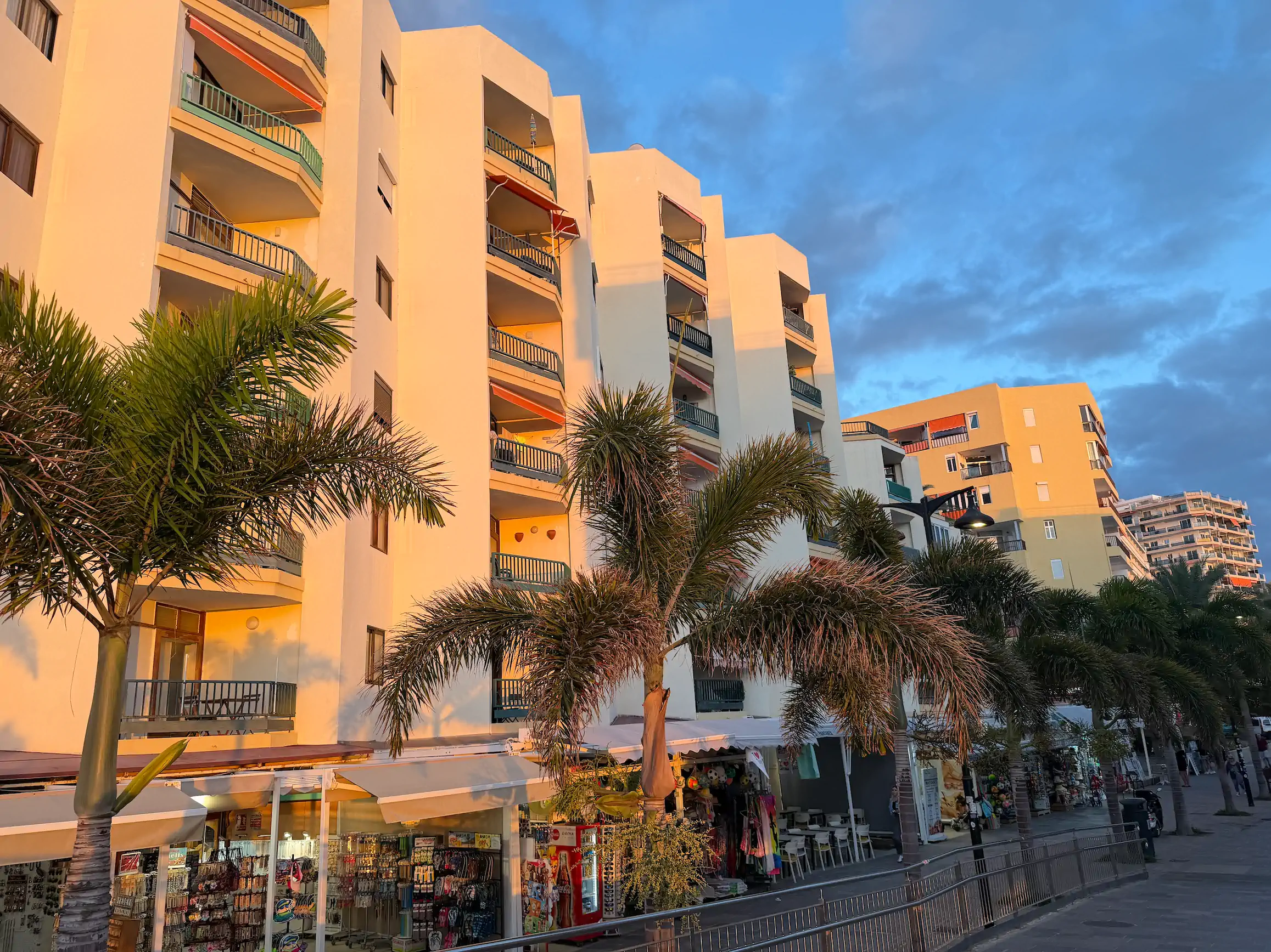 Budynek apartamentowy w ciepłym świetle zachodzącego słońca z pasażem handlowym i sklepami z pamiątkami na parterze