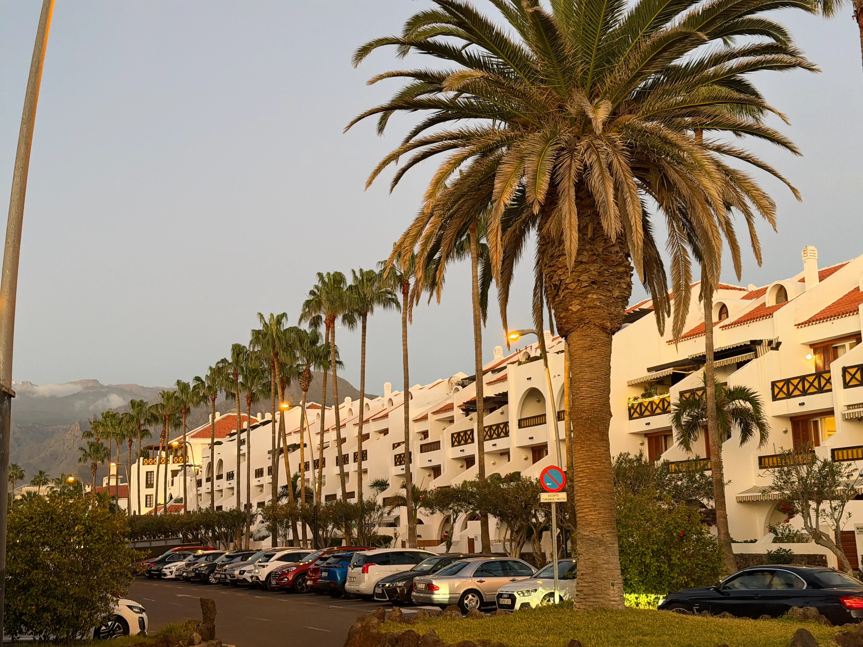 Widok na apartamentowiec na Teneryfie, obok kalkulator i notatnik z wyliczeniami kosztów