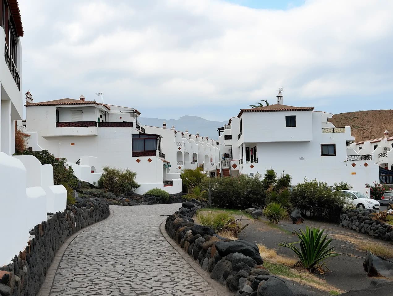 Zadbany, biały kompleks domów szeregowych na Teneryfie z alejkami i wulkanicznymi kamieniami