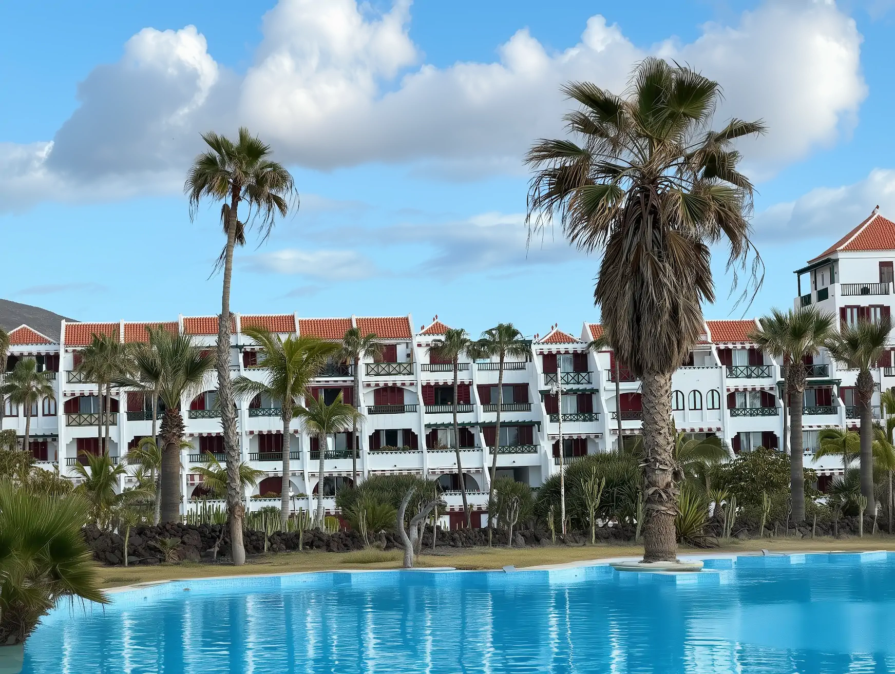 Salon mieszkania na Teneryfie z widokiem na ocean, na stole laptop i dokumenty z kosztami