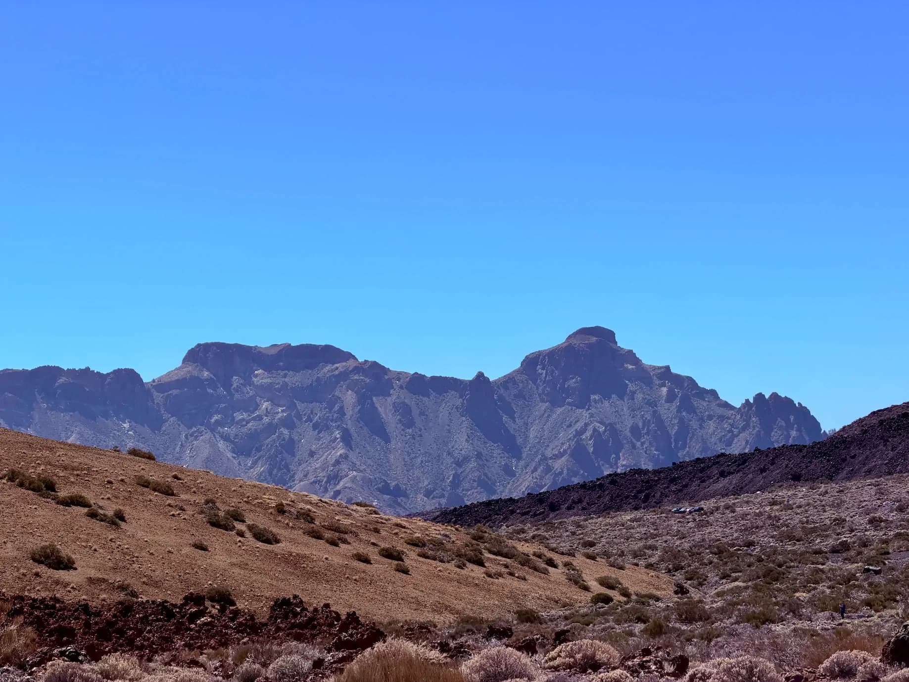 Surowy, wulkaniczny krajobraz Parku Narodowego Teide na Teneryfie z górami w tle i błękitnym niebem