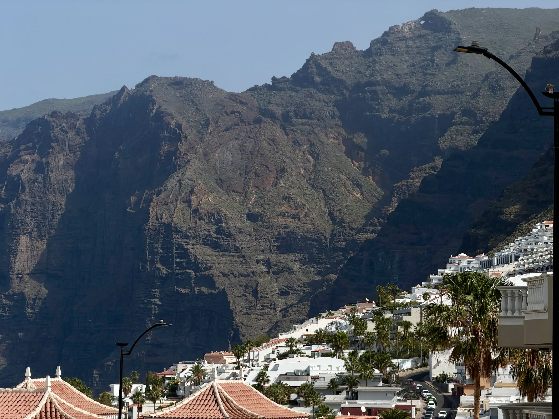 Majestatyczne klify Los Gigantes na Teneryfie z widokiem na białe apartamentowce na wzgórzu