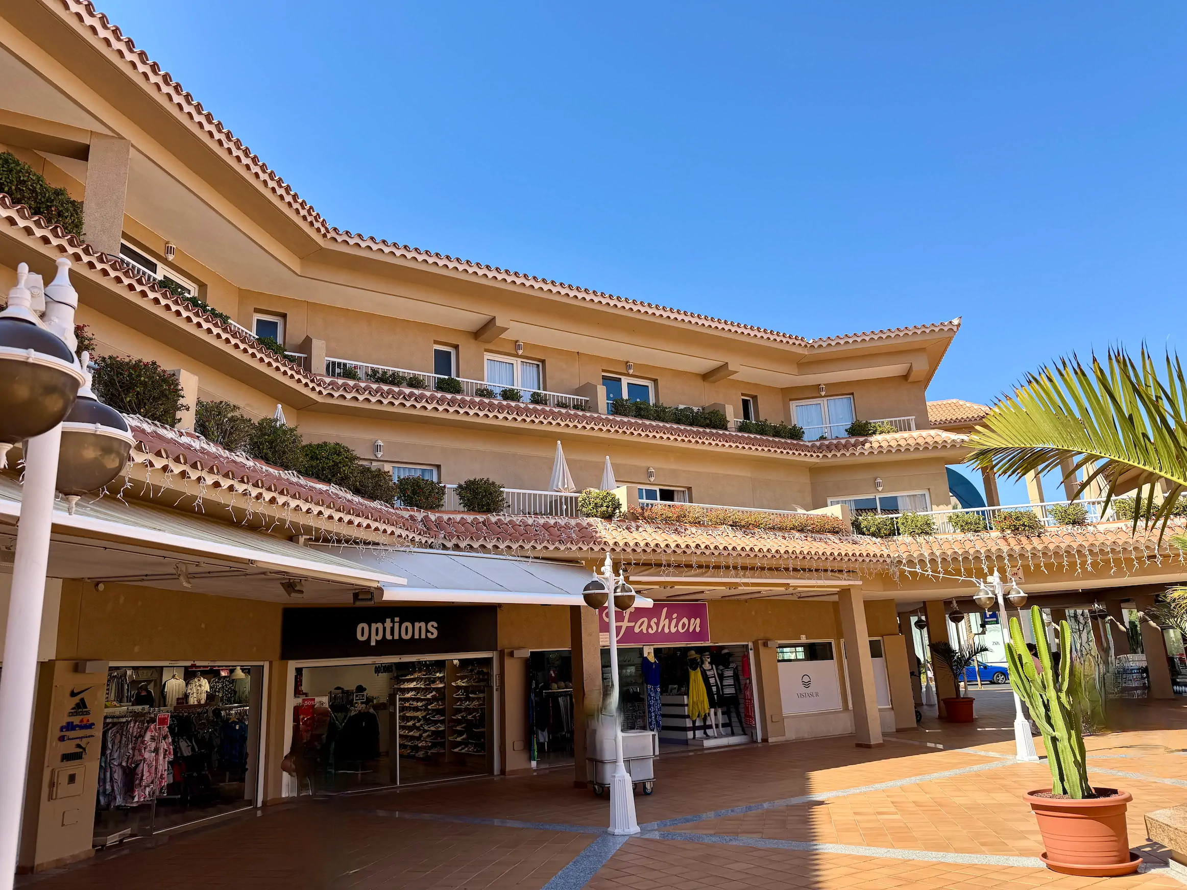 Elegancki wielofunkcyjny kompleks na Teneryfie: na dole butiki odzieżowe, na górze apartamenty z tarasami i tradycyjną dachówką