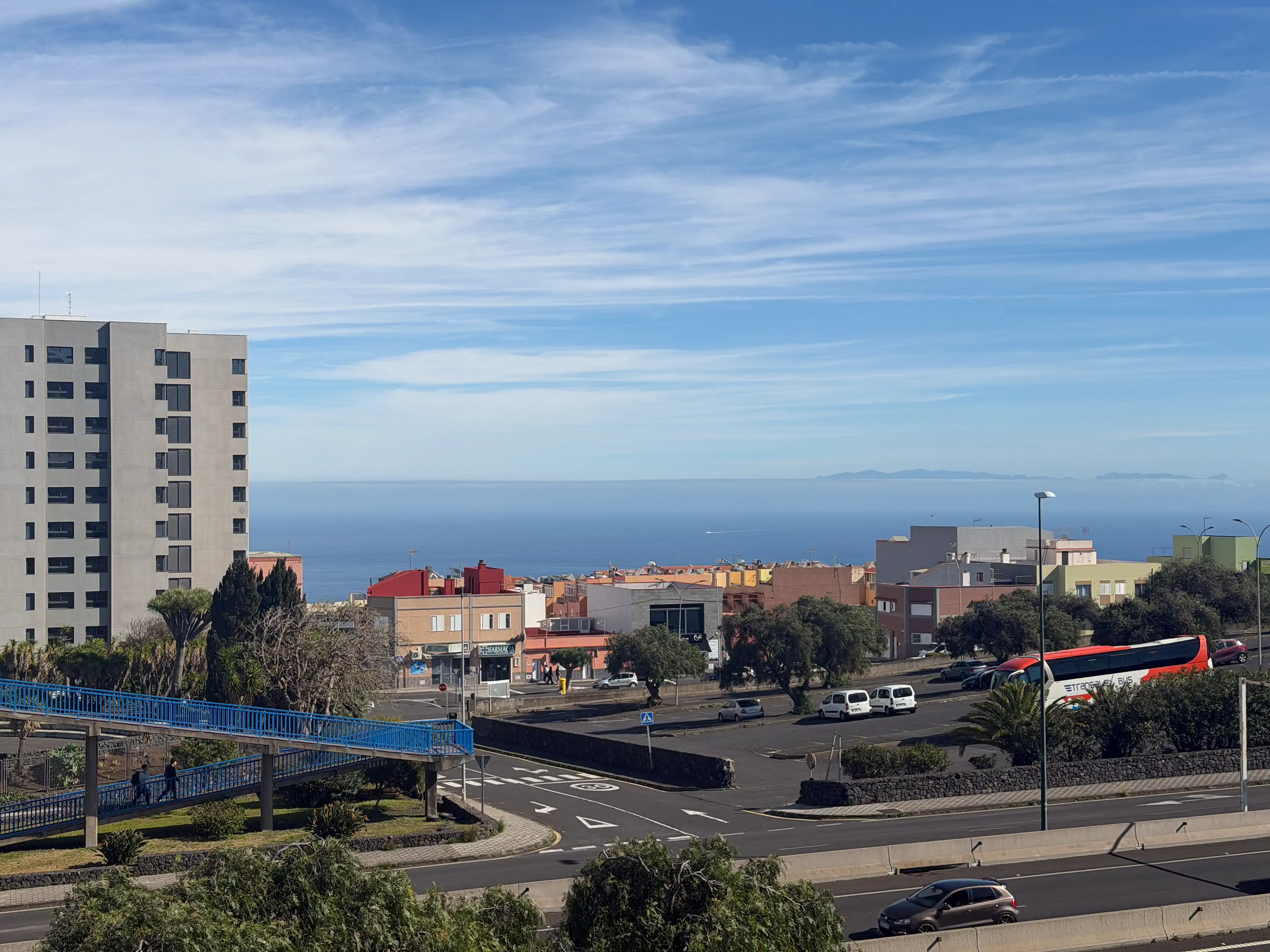 Widok z La Laguny na ocean z wyraźnym zarysem Gran Canarii na horyzoncie, na pierwszym planie bloki mieszkalne i zieleń