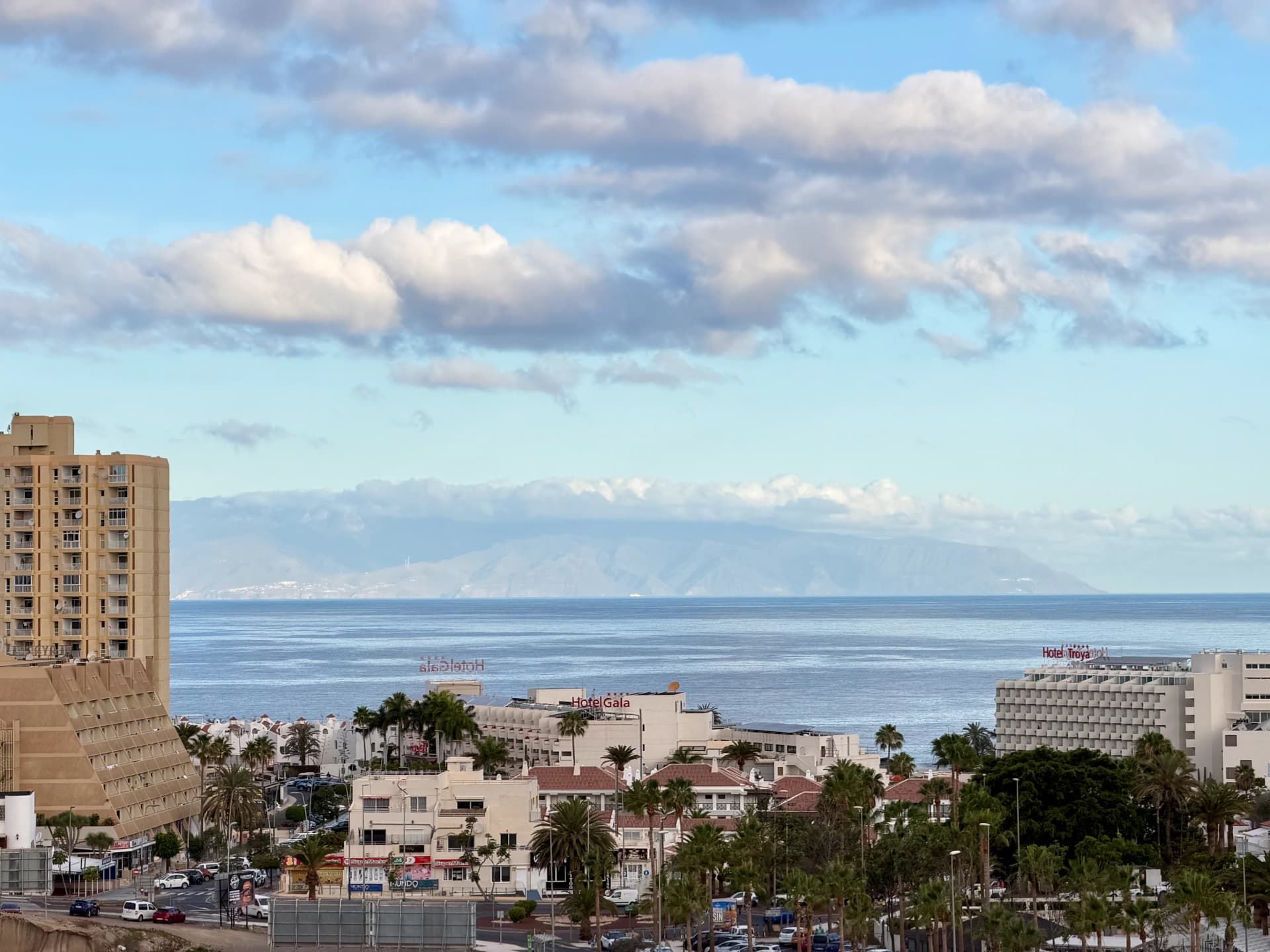 Panoramiczny widok z Teneryfy na ocean i sąsiednią wyspę La Gomera, na pierwszym planie hotele w Playa de las Americas